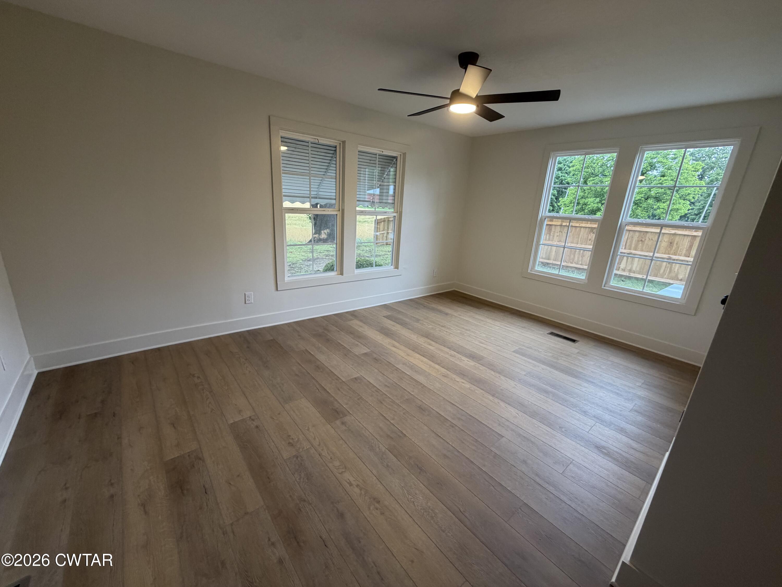 16 Manner Frank Road Milan, TN 38358 - Photo 14 of 25 an empty room with wooden floor ceiling fan and windows