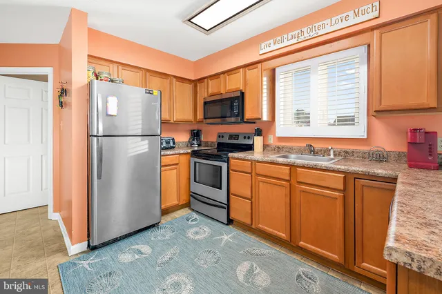 a kitchen with stainless steel appliances granite countertop a refrigerator a sink a stove a microwave and island