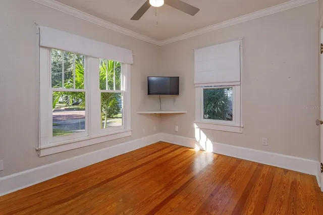 a view of empty room with wooden floor and fan