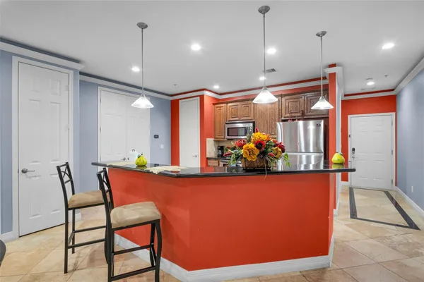 a room with stainless steel appliances kitchen island granite countertop dining table chairs and a large window