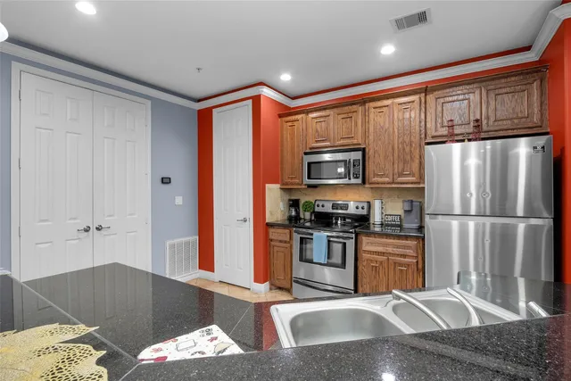 a kitchen with stainless steel appliances granite countertop a refrigerator sink and stove