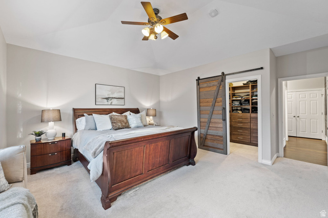 6208 West Bull River Road Highland, UT 84003 - Photo 30 of 90 Vaulted ceiling bedroom featuring a wood-finish ceiling fan with integrated lighting, soft carpet flooring, and a modern barn door opening to a built-in closet system