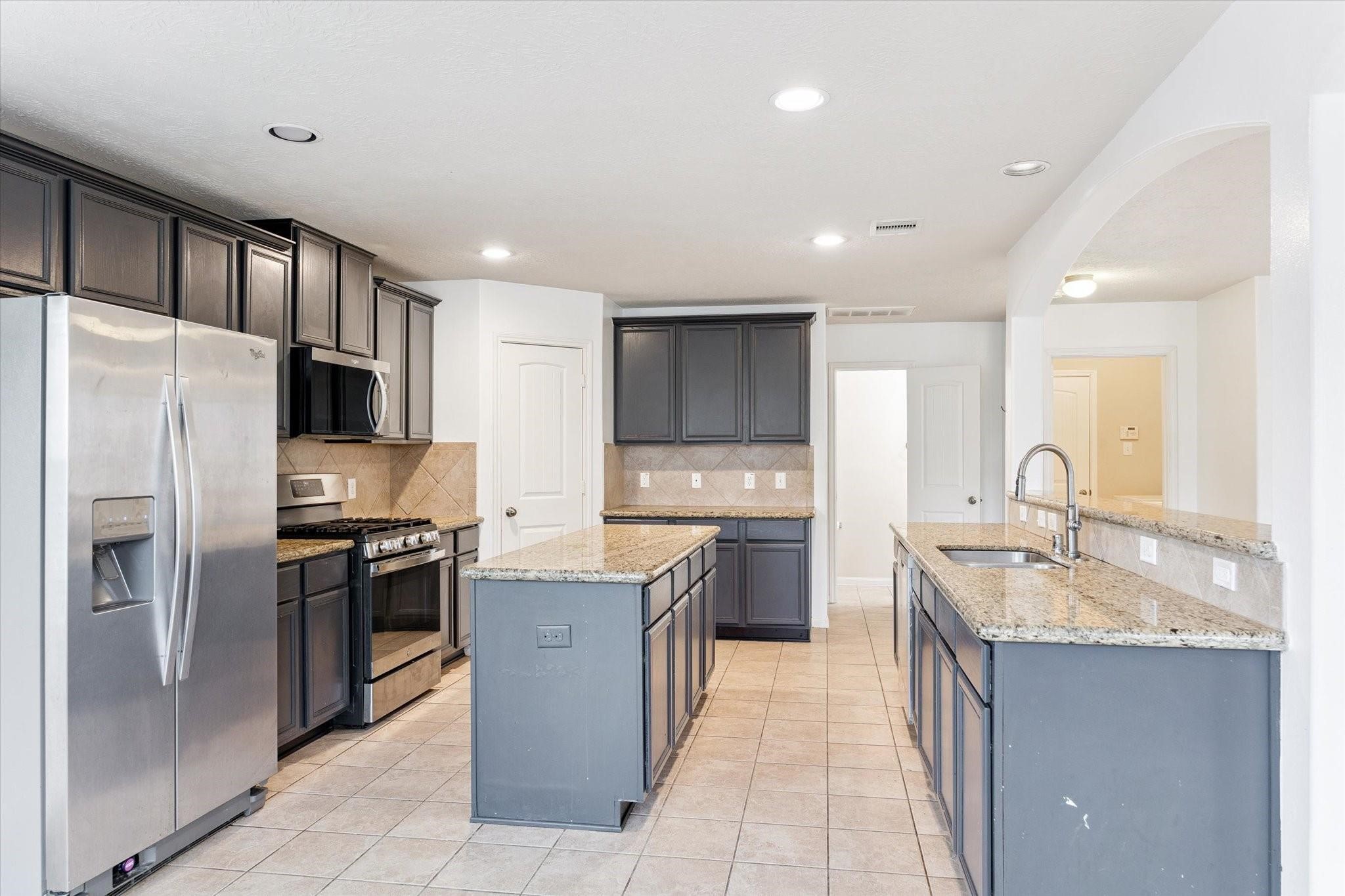 11718 Red Hummingbird Drive Houston, TX 77047 - Photo 4 of 13 a kitchen with stainless steel appliances granite countertop a refrigerator stove a sink and a microwave