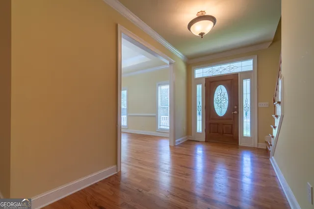 a view of an empty room with wooden floor and a ceiling fan