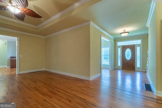 a view of an empty room with wooden floor and a window