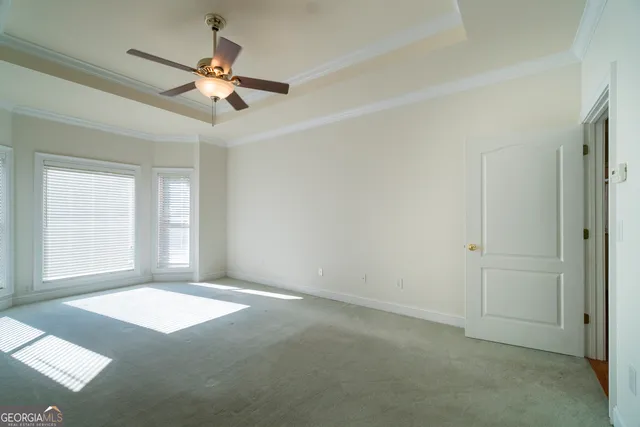 an empty room with a fan & a window