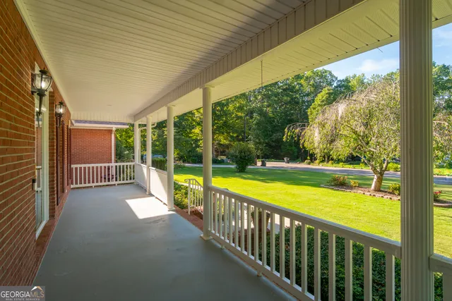a view of an empty room with chandelier fan and wooden floor