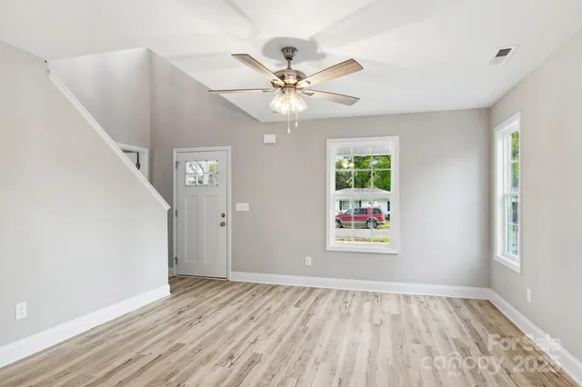 a view of an empty room with window and wooden floor