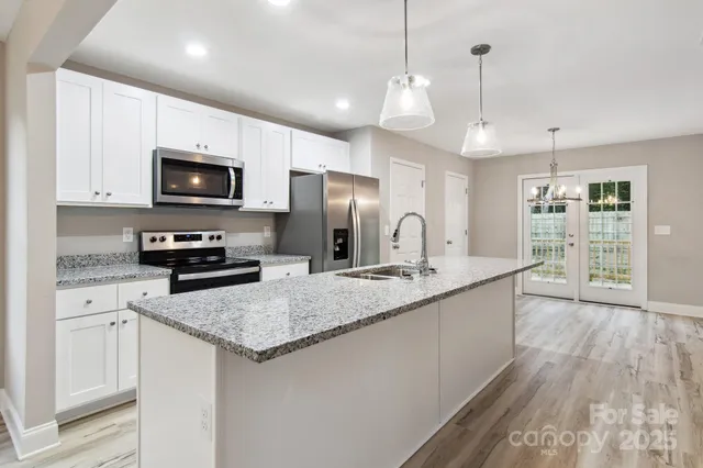 a kitchen with stainless steel appliances granite countertop a sink a stove a microwave a center island and cabinets
