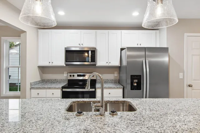 a kitchen with stainless steel appliances granite countertop a sink a stove and a refrigerator