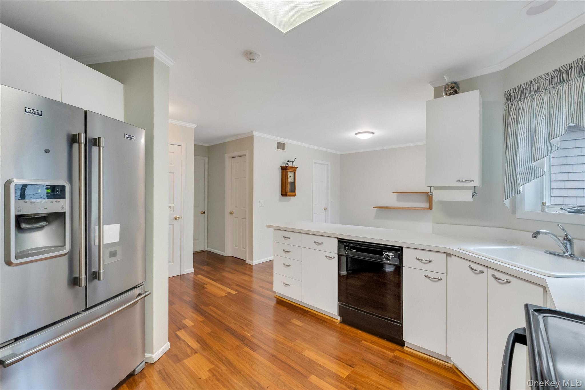 22 Kettle Hole Road Manorville, NY 11949 - Photo 12 of 39 Kitchen featuring wood-finish flooring, white cabinetry, integrated stainless steel refrigerator, and built-in dishwasher