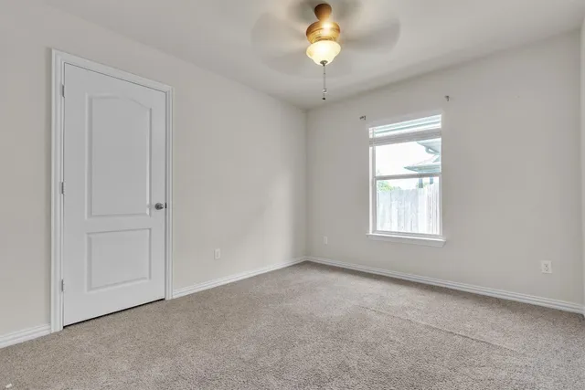 an empty room with a chandelier fan and windows