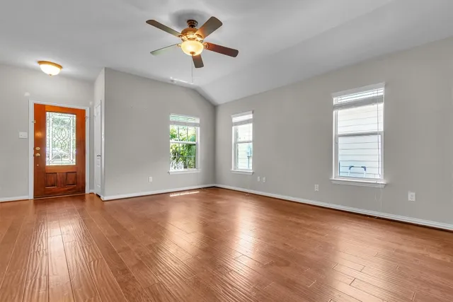 an empty room with wooden floor and windows