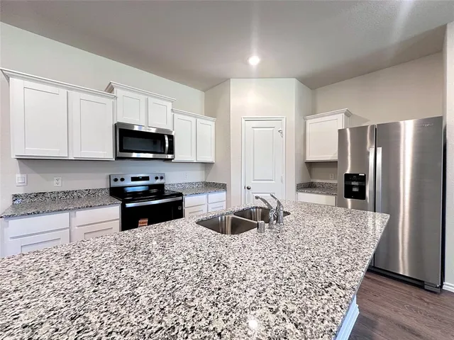 a kitchen with stainless steel appliances granite countertop a refrigerator stove microwave and sink