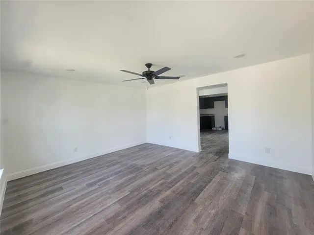 a view of a room with wooden floor and a ceiling fan