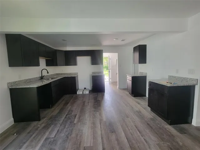 a living room with stainless steel appliances kitchen island granite countertop a sink wooden floor and view living room