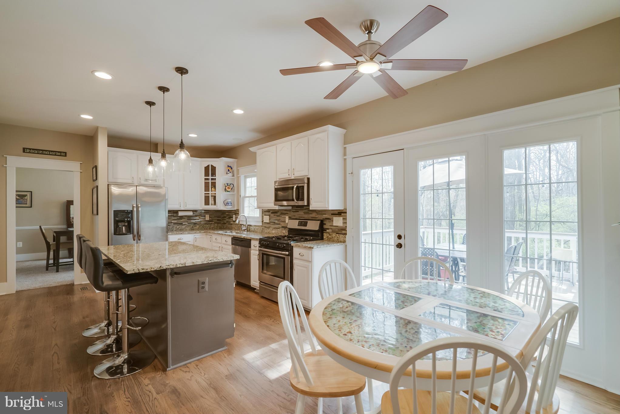 8759 Center Road Springfield, VA 22152 - Photo 8 of 30 a dining room with stainless steel appliances kitchen island granite countertop a table chairs and a refrigerator