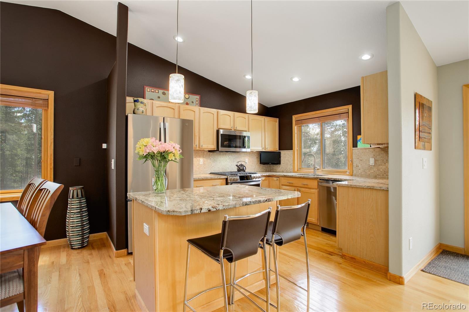 8360 South Warhawk Road Conifer, CO 80433 - Photo 12 of 40 a kitchen with stainless steel appliances kitchen island granite countertop a refrigerator and microwave