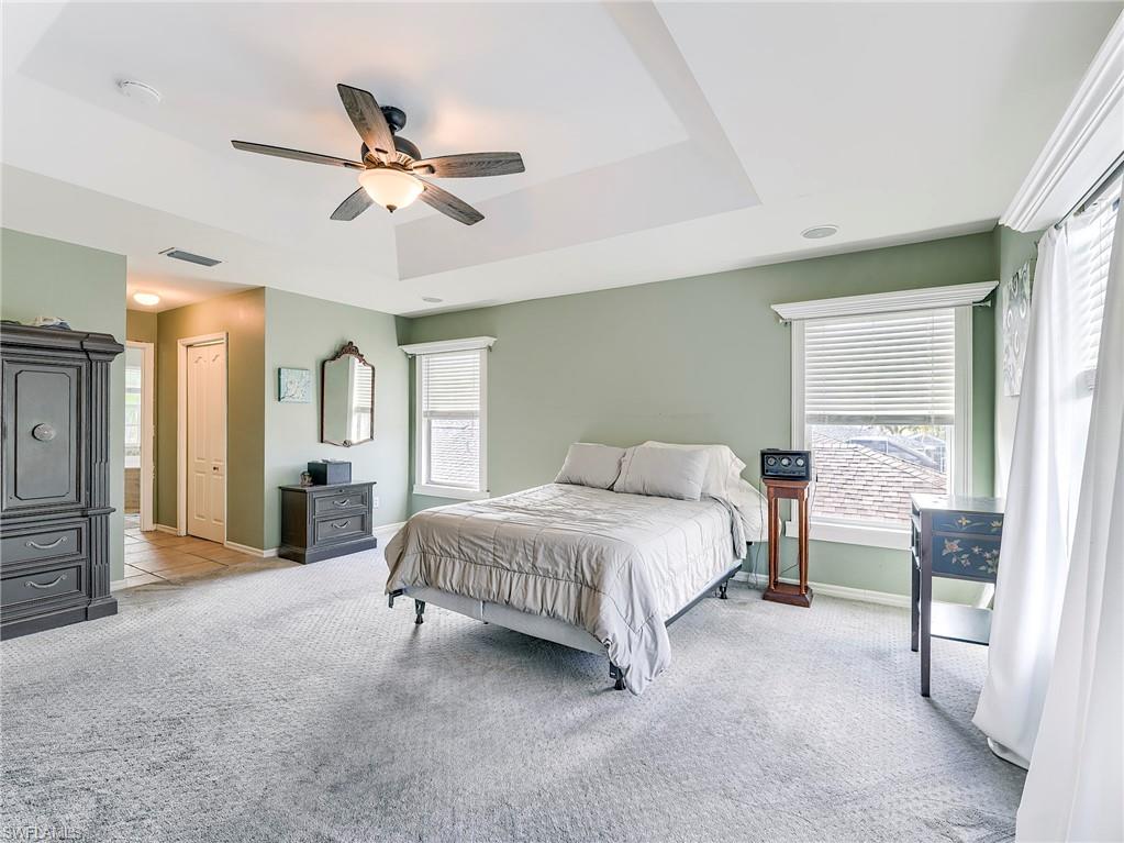 21281 Braxfield Loop Estero, FL 33928 - Photo 19 of 42 a spacious bedroom with a bed and a chandelier