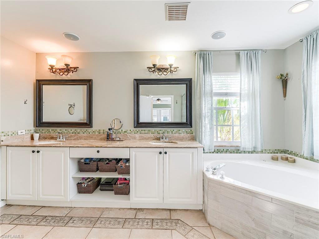 21281 Braxfield Loop Estero, FL 33928 - Photo 20 of 42 a bathroom with a tub a double vanity sink and mirror