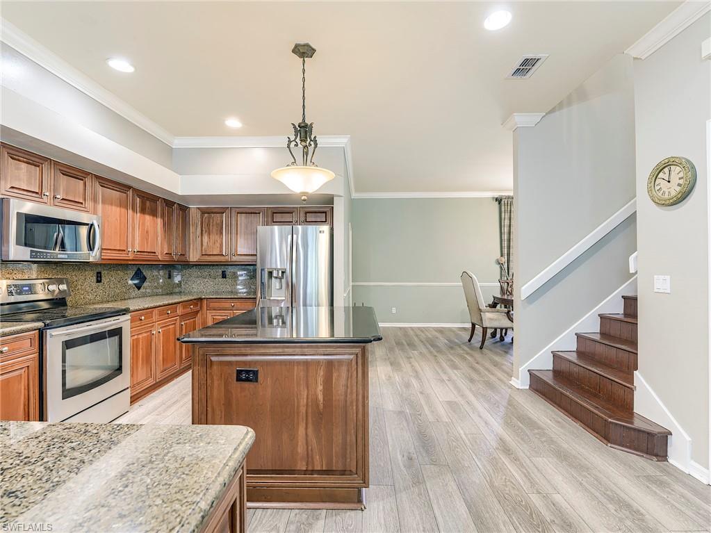 21281 Braxfield Loop Estero, FL 33928 - Photo 9 of 42 a kitchen with stainless steel appliances granite countertop a refrigerator a stove a sink dishwasher and white cabinets with wooden floor