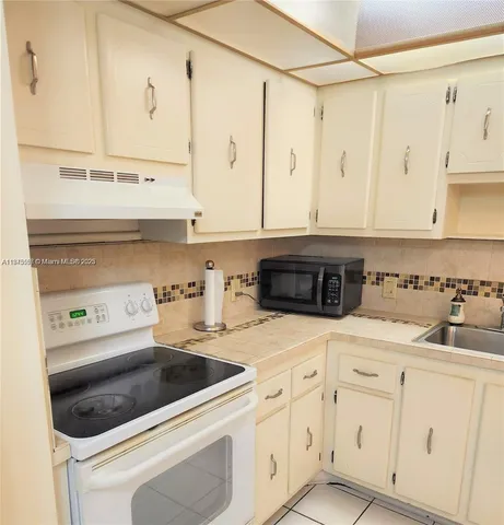 a kitchen with white cabinets and appliances