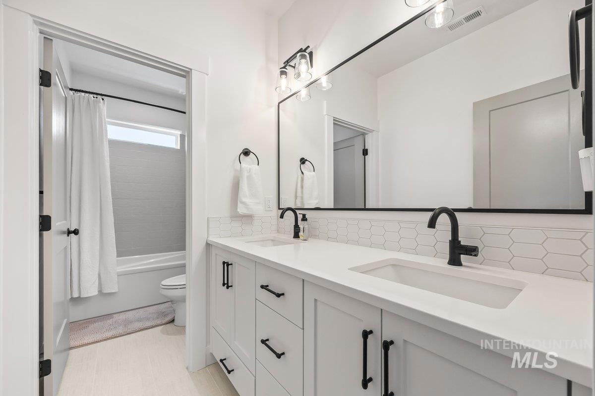 13746 North Ruffed Grouse Way Boise, ID 83714 - Photo 33 of 43 Bathroom featuring double vanity, decorative backsplash, and shower / bath combination with curtain