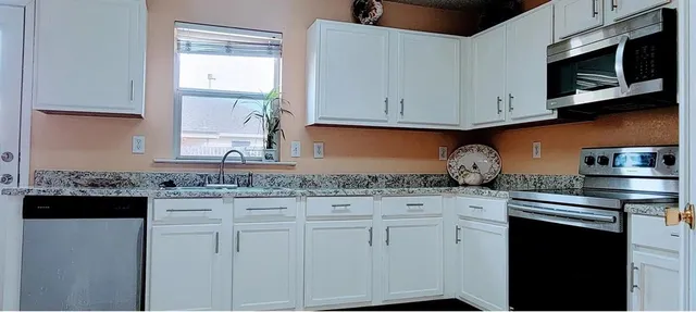 a kitchen with stainless steel appliances granite countertop white cabinets sink and dishwasher