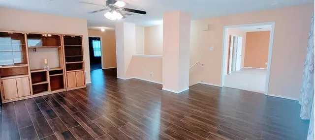 an empty room with wooden floor closet and windows