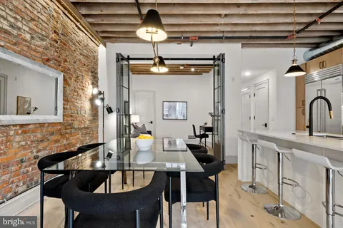 a kitchen with stainless steel appliances kitchen island granite countertop a dining table chairs and a refrigerator