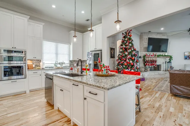 a kitchen with stainless steel appliances granite countertop a sink dishwasher and a flat screen tv
