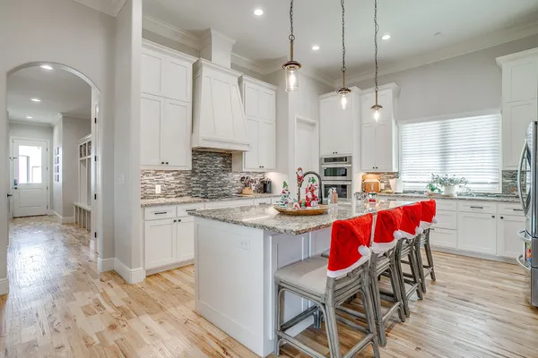 a kitchen with stainless steel appliances kitchen island granite countertop a table chairs sink and cabinets