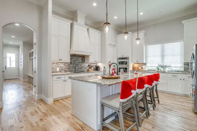 a kitchen with stainless steel appliances kitchen island granite countertop a table chairs sink and cabinets