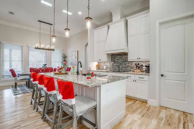 a kitchen with kitchen island granite countertop a sink dining table chairs and white cabinets