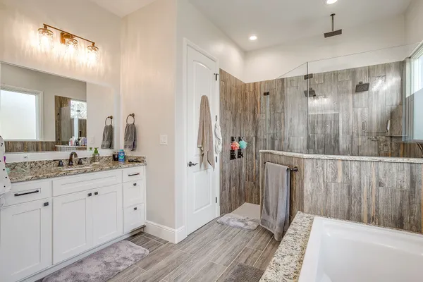 a bathroom with a granite countertop sink a mirror a vanity and a shower