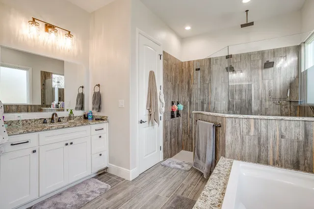 a bathroom with a granite countertop sink a mirror a vanity and a shower