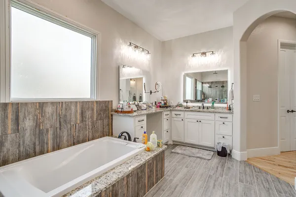 a spacious bathroom with a tub sink and mirror