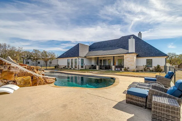 a view of a house with pool and chairs