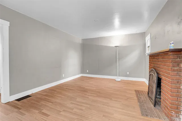 a view of empty room with wooden floor and fireplace