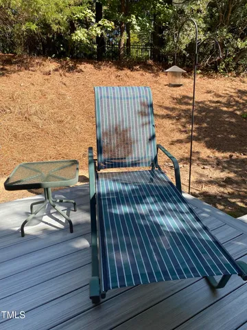 a view of a patio with table and chairs under an umbrella with a small garden