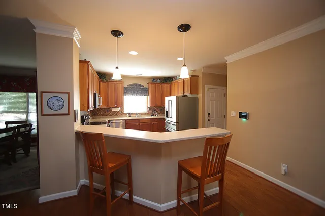 a kitchen with stainless steel appliances kitchen island a table chairs in it and wooden floors