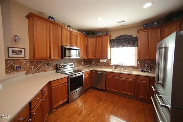 a kitchen with stainless steel appliances granite countertop a stove top oven a sink dishwasher a refrigerator and a microwave