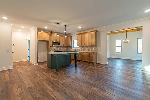 a kitchen with stainless steel appliances a stove a sink and white cabinets with wooden floor