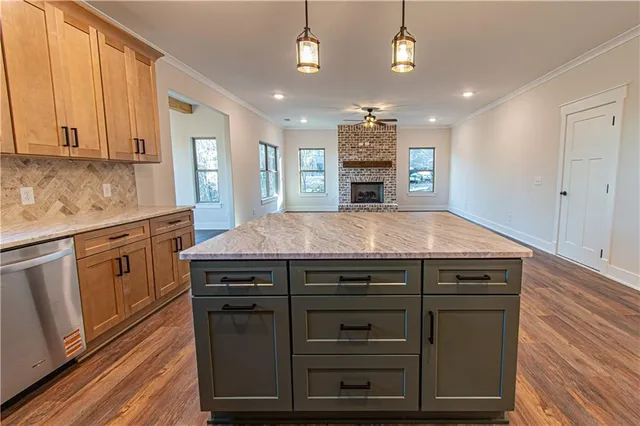 a kitchen with stainless steel appliances granite countertop a stove a sink dishwasher a refrigerator white cabinets and wooden floor next to a window