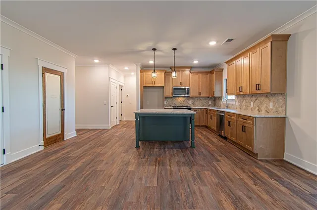 a large kitchen with stainless steel appliances granite countertop a stove and a wooden floors