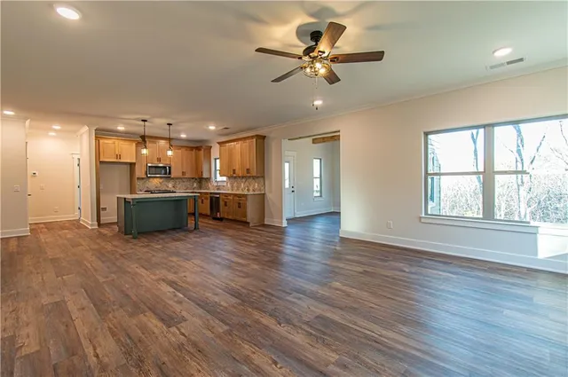 an empty room with wooden floor fireplace and windows