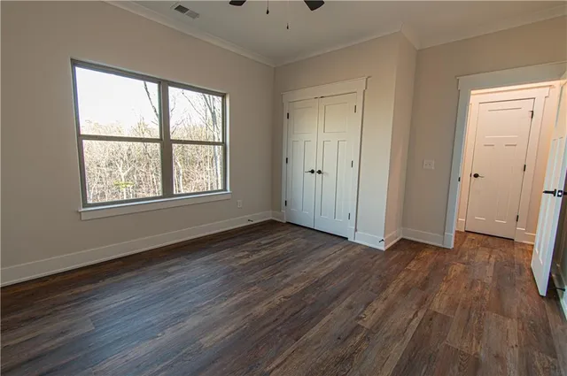 an empty room with wooden floor chandelier fan and windows