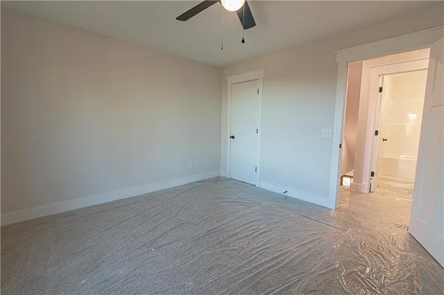 an empty room with a ceiling fan and carpet