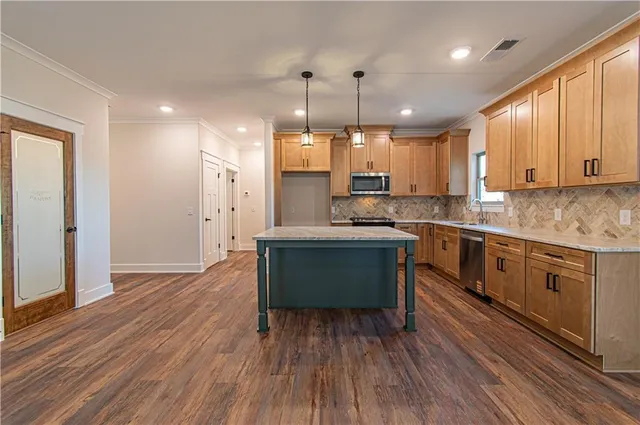 a kitchen with kitchen island a sink stainless steel appliances and cabinets