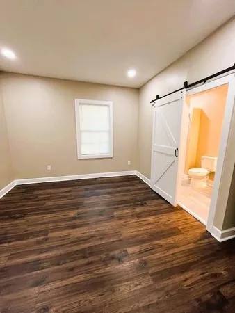 an empty room with wooden floor and windows with curtains